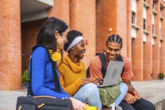Group of diverse university students smiling and interacting outdoors, using a laptop, representing