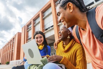 Group of diverse university students enjoying a moment of laughter while using a laptop together on