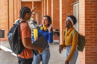 Group of diverse university students on campus, one male and two females, standing in a brick