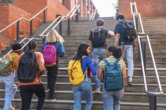 Group of young, multi ethnic university students with backpacks ascending outdoor stairs at a