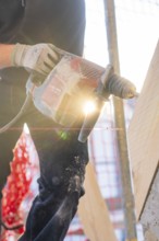 Drilling work in sunlight on construction site with wooden elements, carpentry construction, roof
