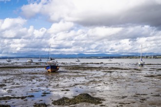 Boats on mud of Forth Estuary over Blackness Castle, Blackness, Scotland, UK