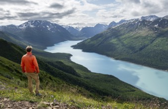 Mountaineer enjoys views of blue lake and mountains on Twin Peaks Trail, Eklutna Lake, Chugach