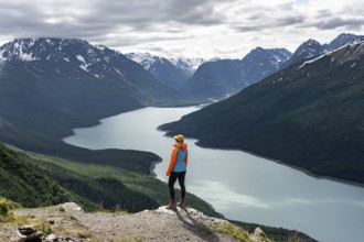 Female mountaineer enjoying views of blue lake and mountains on Twin Peaks Trail, Eklutna Lake,
