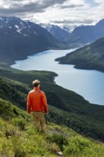 Mountaineer enjoys views of blue lake and mountains on Twin Peaks Trail, Eklutna Lake, Chugach
