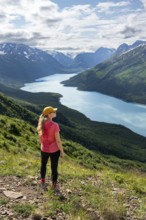 Female mountaineer enjoying views of blue lake and mountains on Twin Peaks Trail, Eklutna Lake,