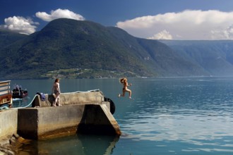 Summer jump into cool water from a jetty in the fjord, Solvorn, Norway