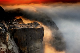 Dramatic view of Prekestolen at sunrise surrounded by clouds and fog