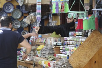 Cosmetics seller at a lively market in Fez, surrounded by goods and buyers, Fez, Morocco