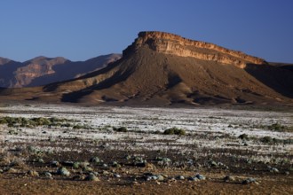 Dramatic rock formations in dry desert landscape under blue sky, Gourrama, Morocco