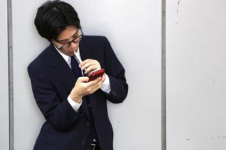 A businessman at Kyoto Central Station, immersed in his smartphone, Kyoto, Japan