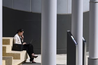 An office lady taking a break from work at Kyoto Central Station, Kyoto, Japan