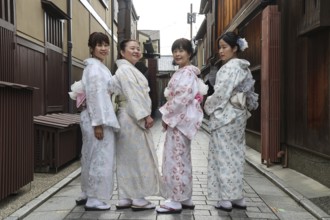 Four woman wearing kimonos pose on Nakamachi Street in Gion, Gion, Kioto, Japan