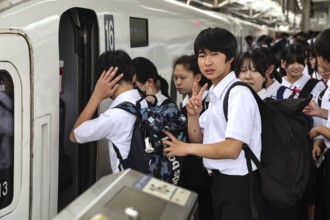 Students wearing school uniforms board a train at the train station in Kyoto, Kyoto, Japan