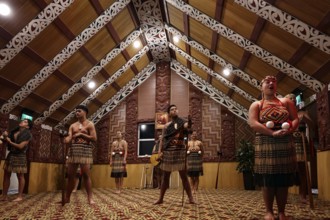 Maori dancers in traditional dress in an ornate meeting house, Rotorua, Te Puia, New Zealand