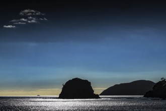 A silhouette of an island against a dark blue sky at sunset, Bay of Islands, New Zealand