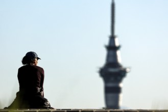 Person sitting in front of Sky Tower and enjoying the view in clear skies, Auckland, New Zealand