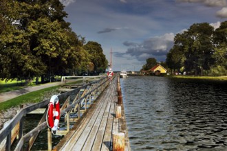 Long wooden walkway along the Göta Canal in a mountain, lined with trees and water under a cloudy