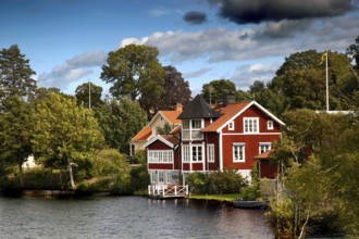 Charming red house on the water of the Göta Canal in Borensberg, surrounded by green nature,