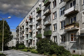 Rows of prefabricated buildings under cloudy sky with adjacent green areas, Liepaja, Karosta,