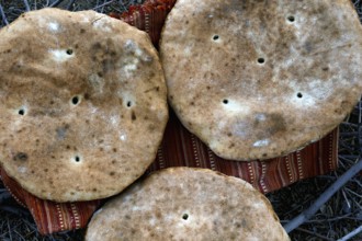Three large flatbread loaves on a support in the desert, Beni Tajite, Morocco