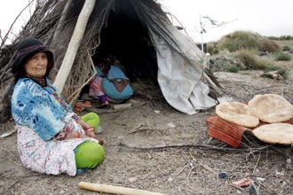 Bedouins baking bread in front of a tent in a natural desert environment, Beni Tajite, Morocco