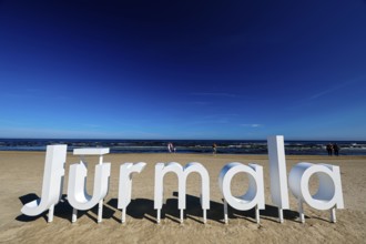 Large Jurmala logo on extensive beach under clear blue sky, Majori, Jurmala, Latvia