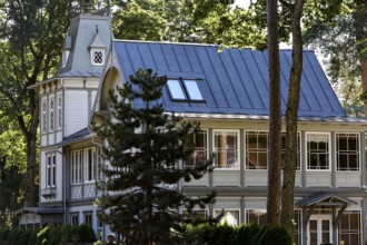 Elegant art nouveau wooden house with eye-catching blue roof under tall trees, Majori, Jurmala,