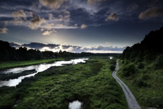 The Windau valley in Kuldiga with lush vegetation and dramatic sky, Kuldiga, Windau, Latvia