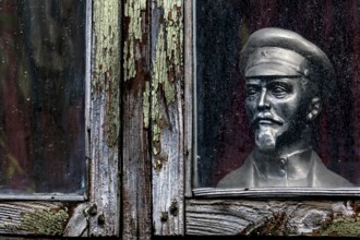 Lenin bust stands behind a dilapidated window in Kuldiga's old town, Kuldiga, Latvia
