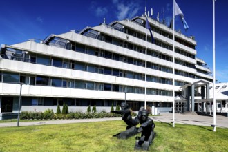 Modern sanatorium building with flags and well-kept green area against blue sky, Vaivari, Jurmala,