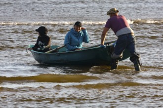 Three people in a small rowing boat on Kolka beach, Kolka, Latvia