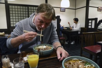 Man enjoying udong ramen in a traditional Japanese restaurant, Kurashiki, Japan