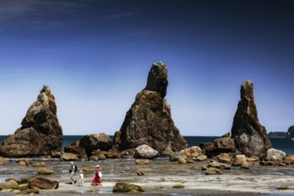 Large coastal rock formations under clear blue sky with walkers, Kushimoto, Japan