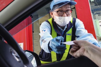 A cashier at a toll station exchanges papers with a motorist, Kobe, Hyogo, Japan