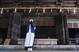 Woman praying in front of a traditional shrine in Kotohira, Kotohira, Japan