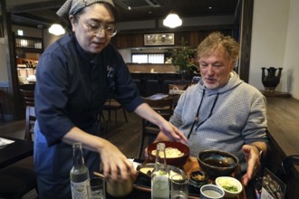 Man receives udon noodles in a traditional restaurant, Kyoto, Okazaki, Japan