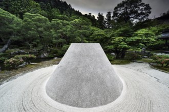 Zen garden with the cone-shaped sand hill Kogetsudai surrounded by green vegetation and trees,