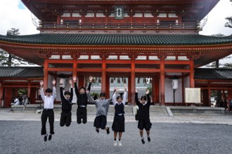 Group of students jump in front of a large torii in Kyoto, Kyoto, Okazaki, Japan
