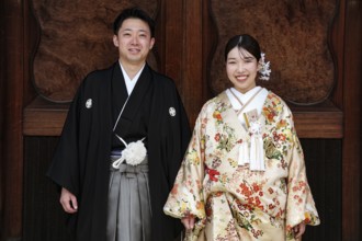 Bride and groom wearing traditional kimonos against a wooden background, Kyoto, Higashiyama, Japan
