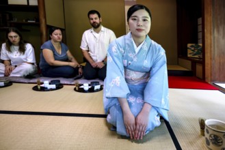 Tea master in blue kimono at tea ceremony, spectator in the background, Kyoto, Higashiyama, Japan