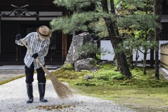 A gardener cultivates the garden with a broom in a traditional setting, Kyoto, Okazaki, Japan