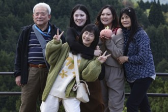 A group of tourists poses happily against a picturesque backdrop in Magome, Magome, Japan
