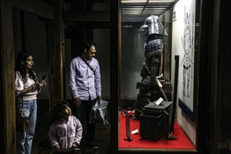 A family looks at samurai armor on display at Matsumoto Castle, Matsumoto, Japan