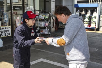 Employee hands something to a customer at a gas station in Kanazawa, Kanazawa, Japan