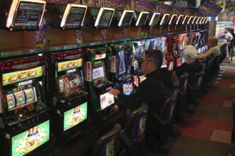 People play pachinko in a busy hall in Osaka, Osaka, Japan