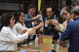 Friends at Kamado Jigoku in Beppu toast with bottles and enjoy the atmosphere, Beppu, Oita, Japan