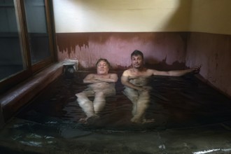 Two men relax in a traditional onsen at Ryokan Asogen
