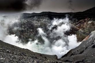 Steaming crater with thick clouds over rocky landscape, Aso, Kumamoto, Japan