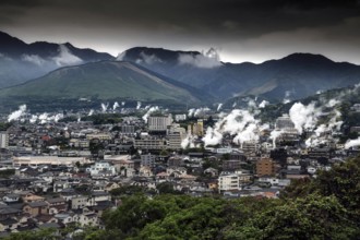 Panorama of a city in mountainous surroundings crossed by rising steam columns, Beppu, Oita, Japan